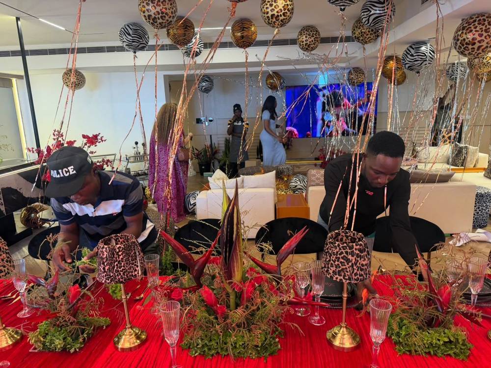 A long red table being dressed with leopard-print lamps and ginger centrepieces for an event