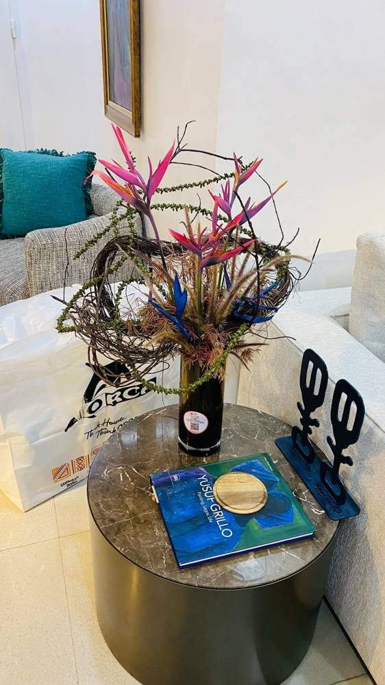 Pink heliconia and blue bird of paradise with a vine ring on a side table