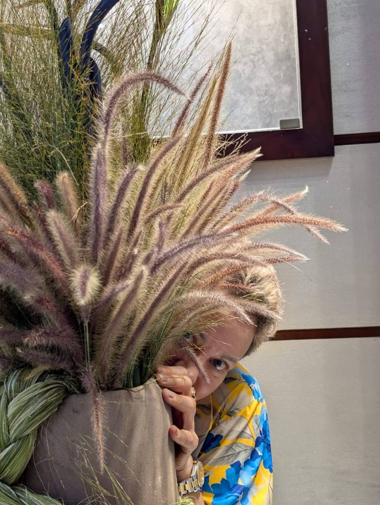 Ilona peering out from behind an armful of fountain grass