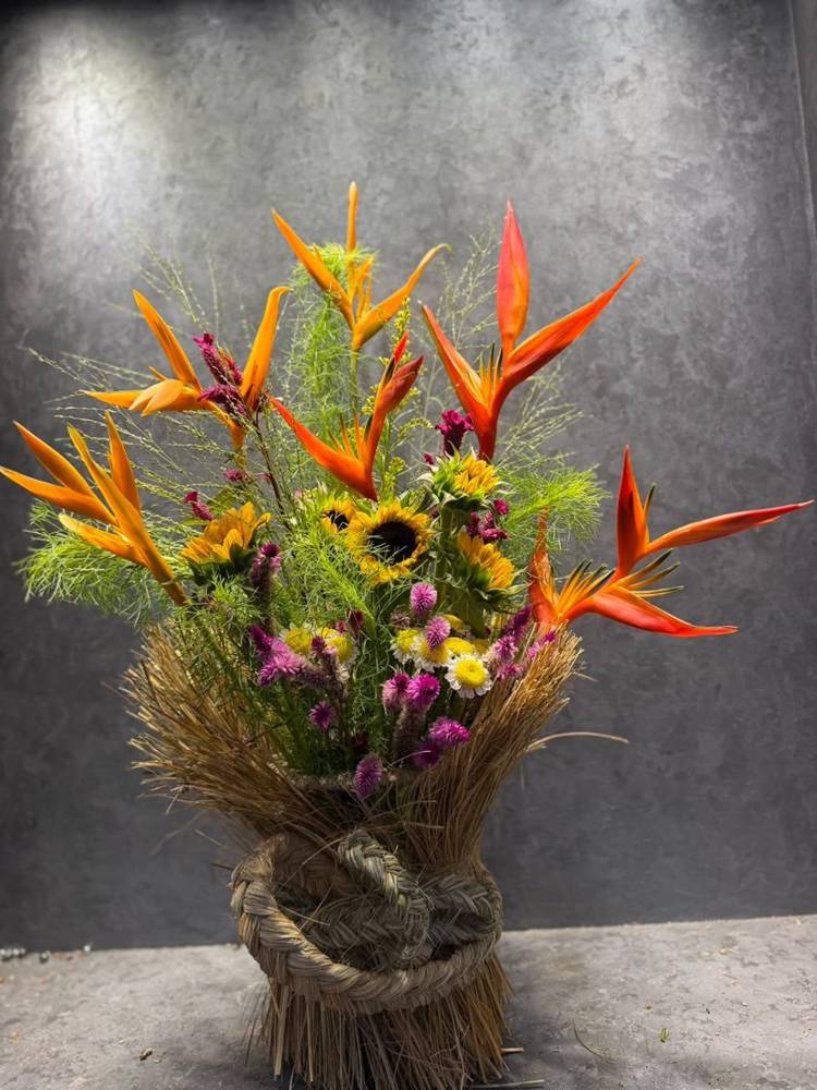 A gold lantern set in sunflowers, celosia and daisies