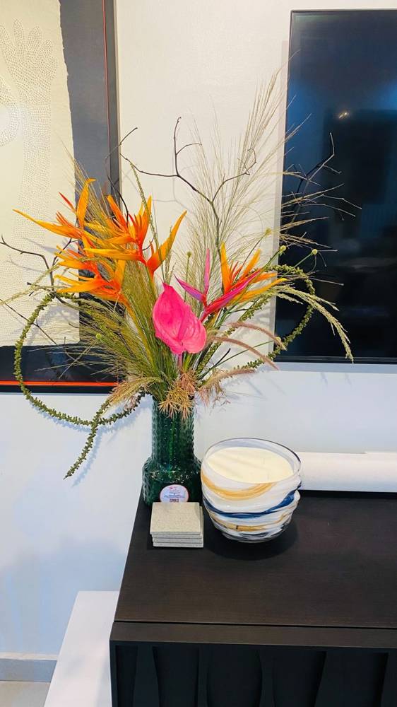 Orange heliconia and yellow orchids in a low nest of grass