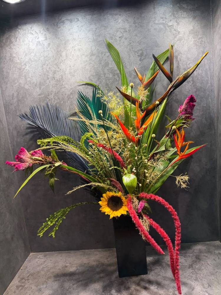 Heliconia, blue bird of paradise and frangipani in a white vase