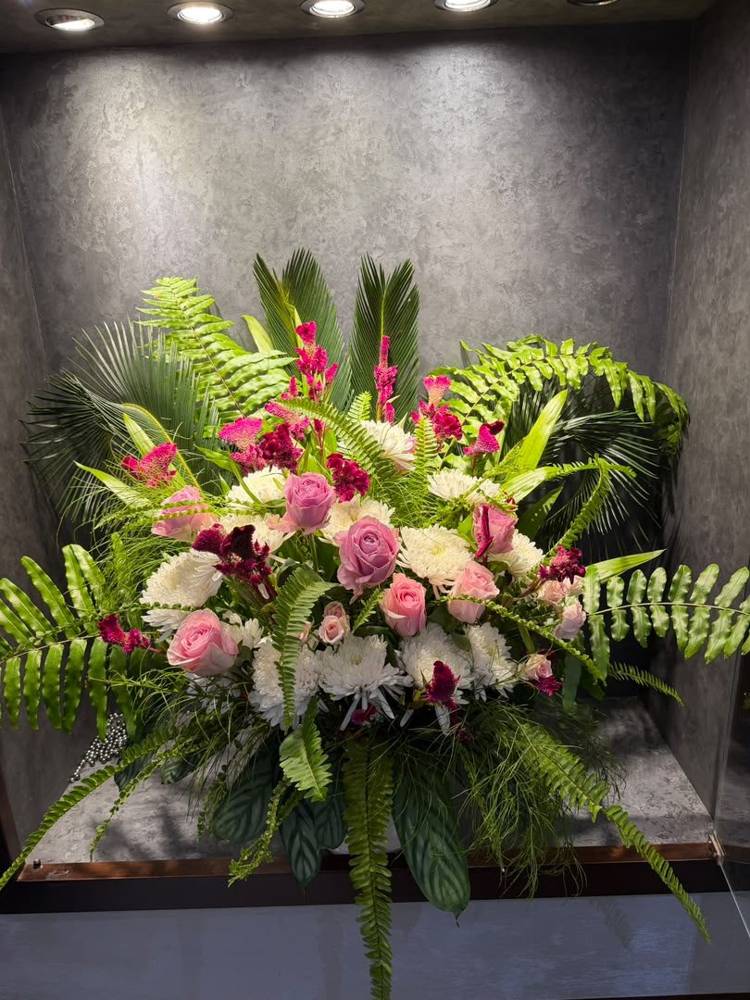 A pink rose and fern garland dressing a wedding car