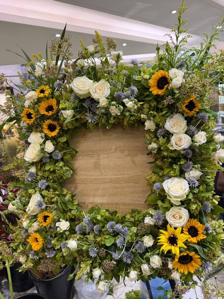 A square wreath of sunflowers, white roses and thistle